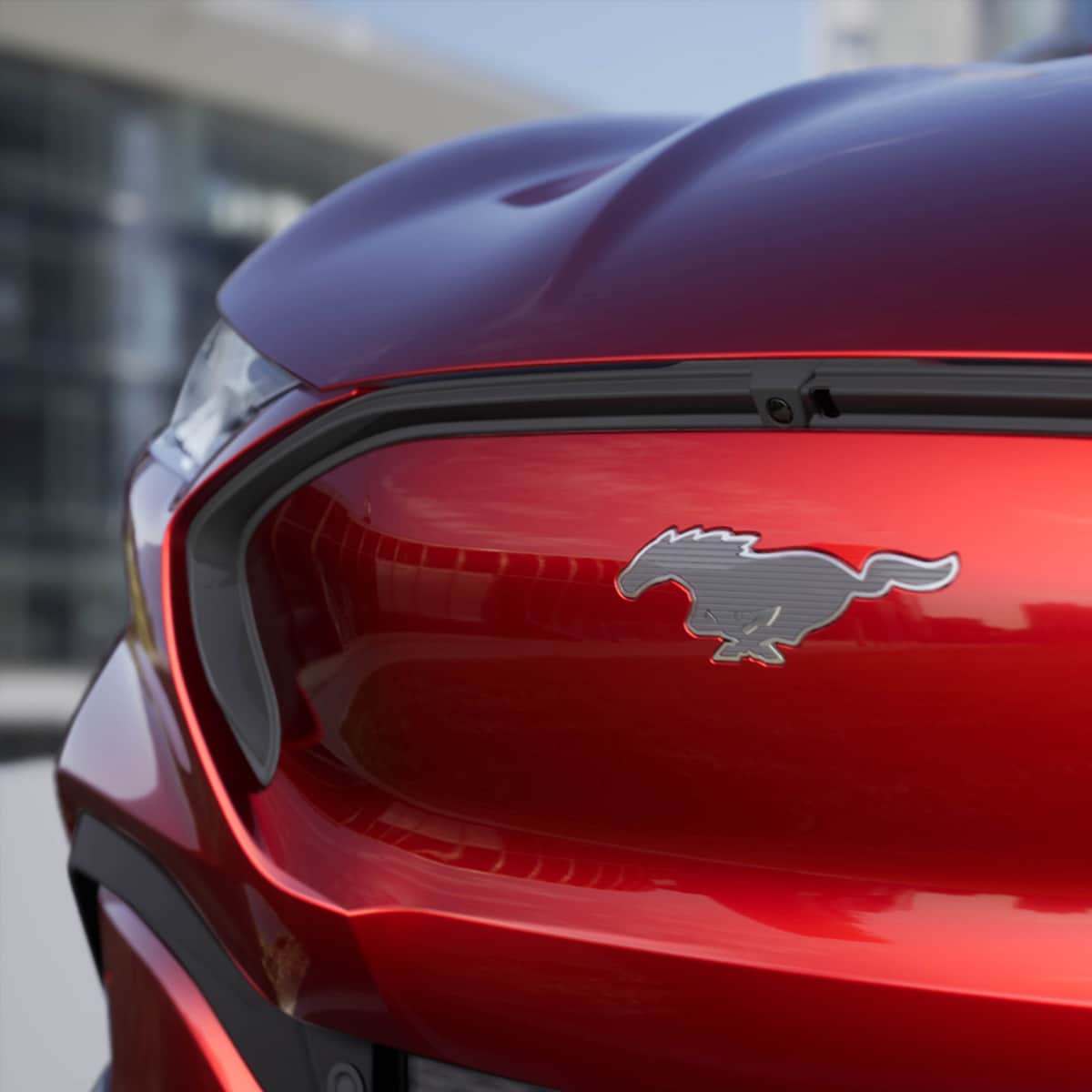 Ford Mustang Mach-E couleur rouge. Vue détaillée de l’avant avec le cheval Mustang argenté