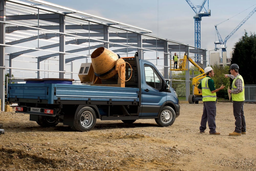 Vue latérale d'un châssis-cabine Ford Transit bleu, chargé sur un chantier.