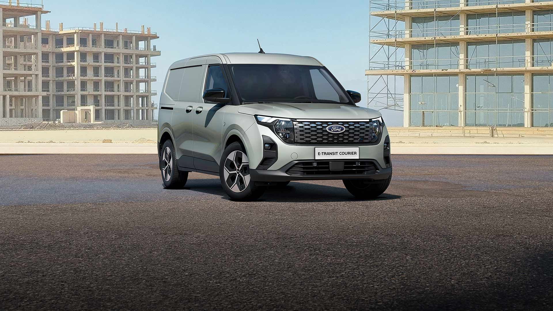 Un Ford E-Transit Courier gris stationné sur une route.