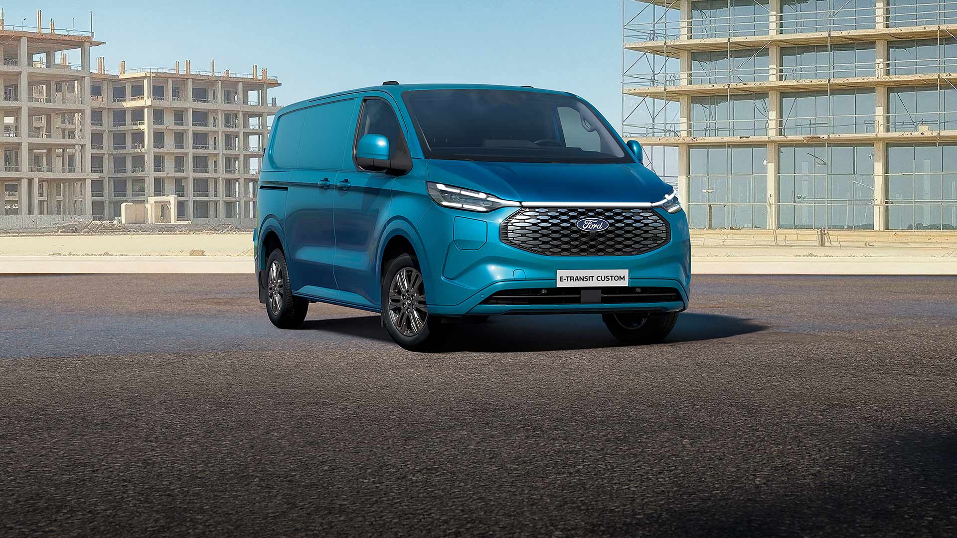 Un Ford E-Transit Custom bleu stationné sur une route.