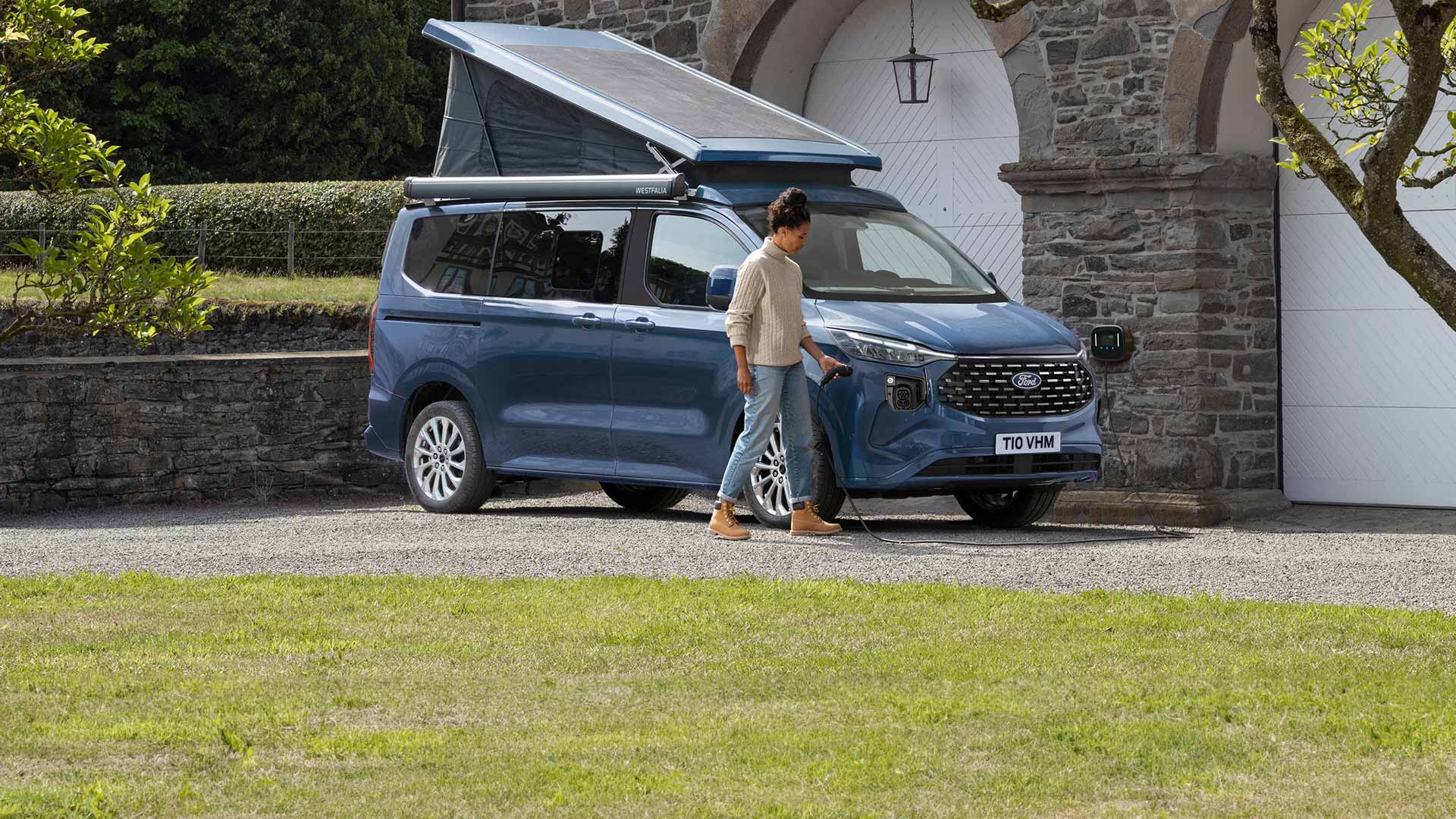 Une femme branche le cable pour charger le Ford Nugget PHEV.