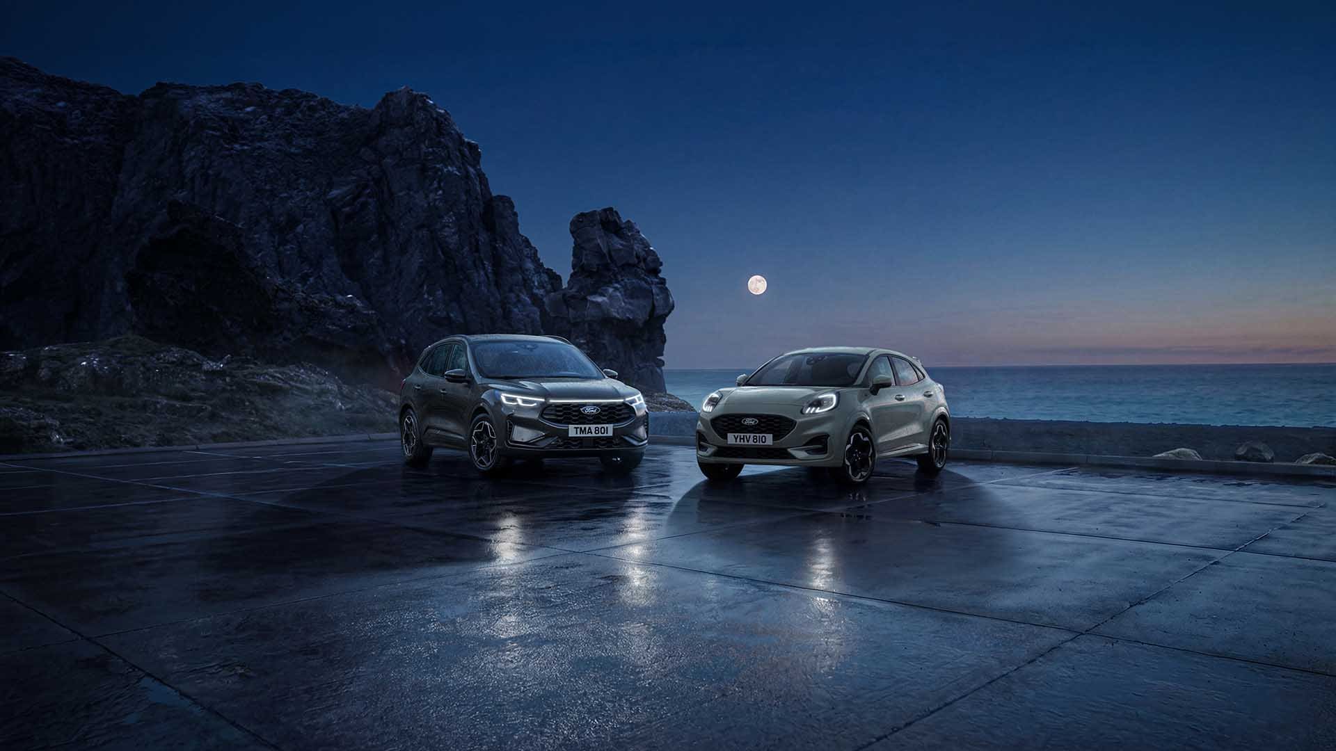 Une Ford Kuga et une Ford Puma stationnées la nuit au bord de la mer sous la pleine lune.