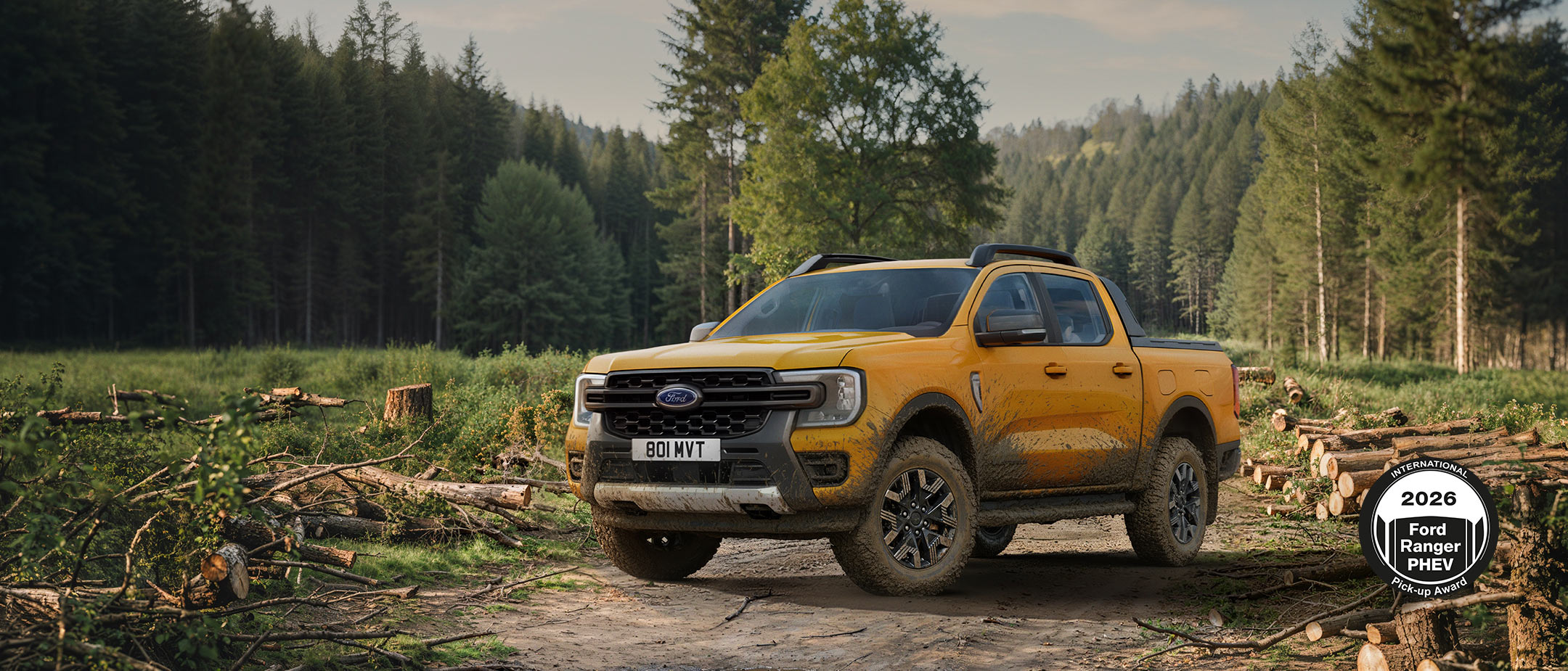 Ford Ranger jaune sur un chemin forestier boueux au milieu de bois coupés en forêt.