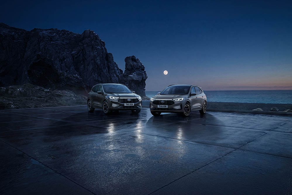 Deux Ford Kuga stationnées la nuit au bord de la mer sous la pleine lune.