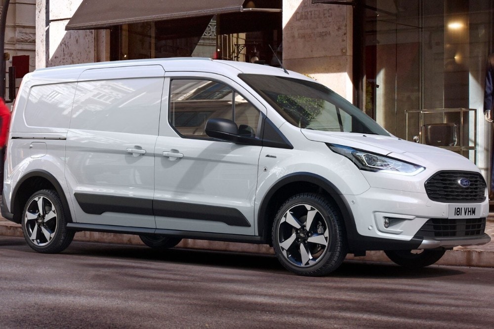 Un fourgon Ford Transit Connect blanc garé devant un bâtiment, vu de trois quarts avant.