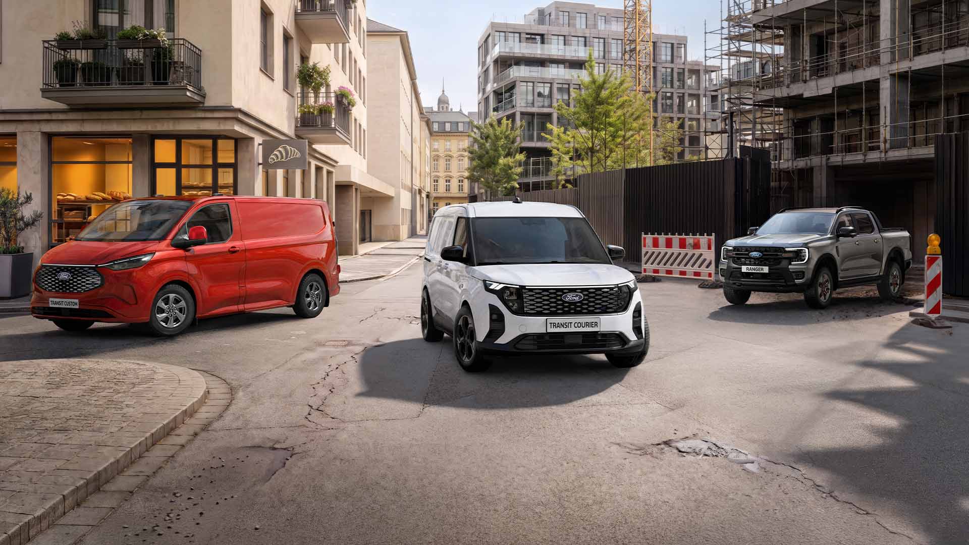 Trois véhicules Ford, un Transit Custom rouge, un E-Transit Custom blanc et un Ranger gris, sont garés dans une rue urbaine.