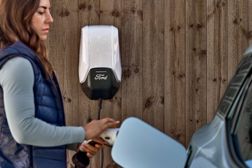 Une femme branche le nouveau Ford Explorer à la Ford Wallbox avec un câble de charge