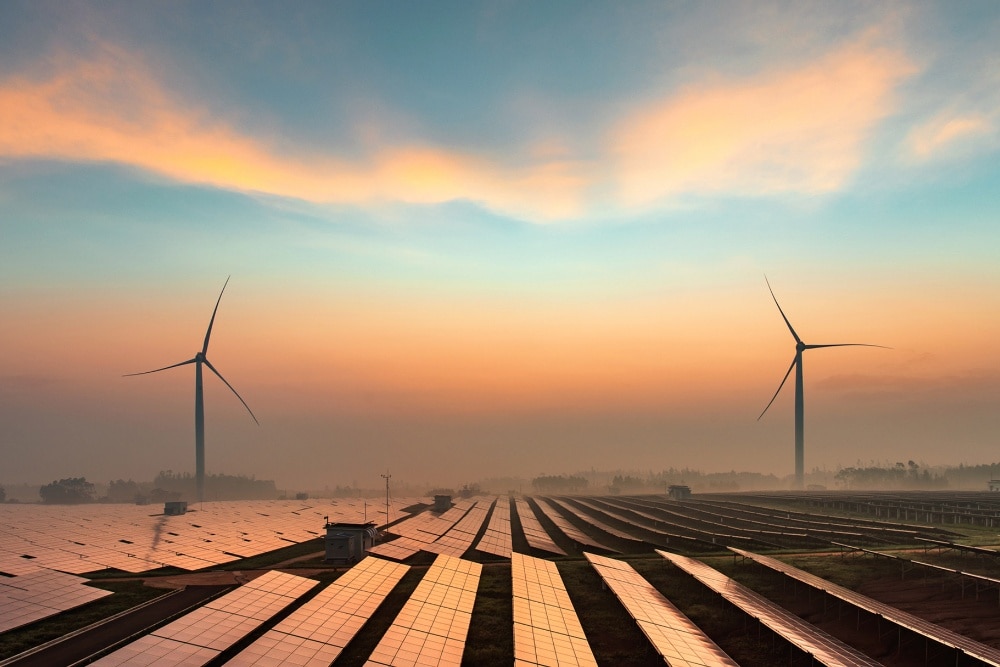 Champ de modules photovoltaïques avec deux éoliennes au loin