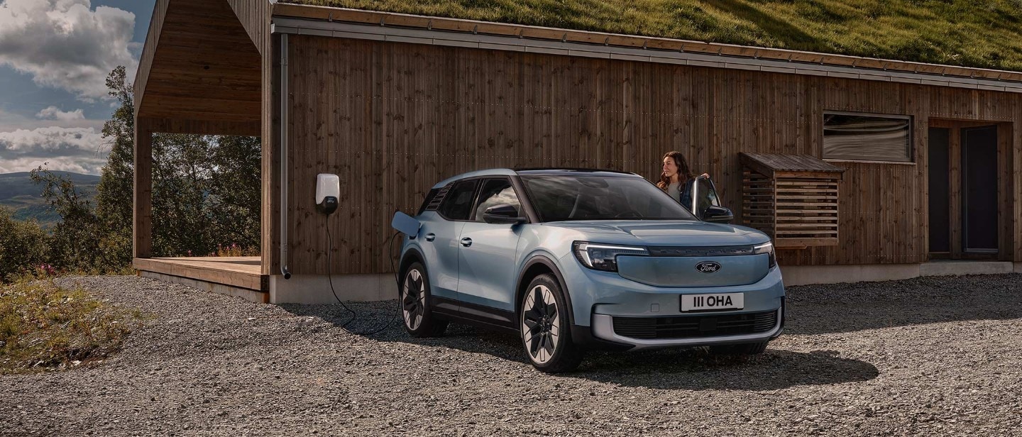 Le nouveau Ford Explorer entièrement électrique, couleur bleu clair, vue de face aux trois quarts, branché à une Wallbox