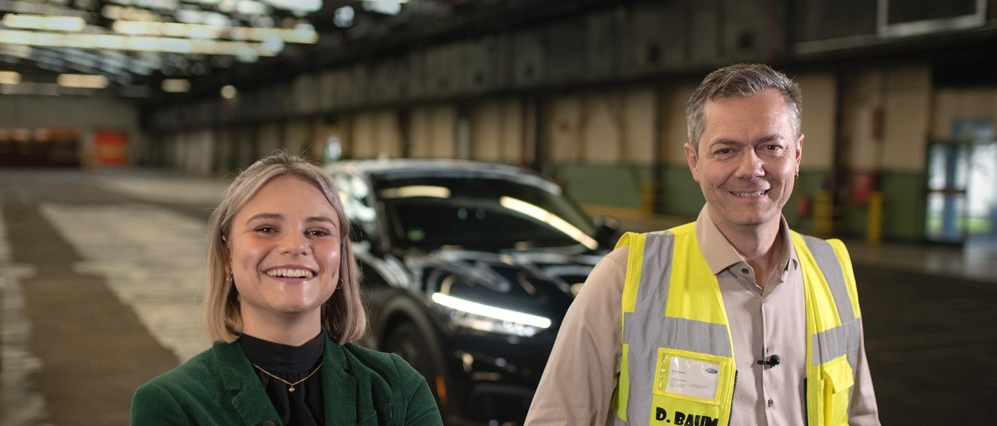 Une jeune femme et un collaborateur de Ford se tiennent dans un hall et sourient à la caméra