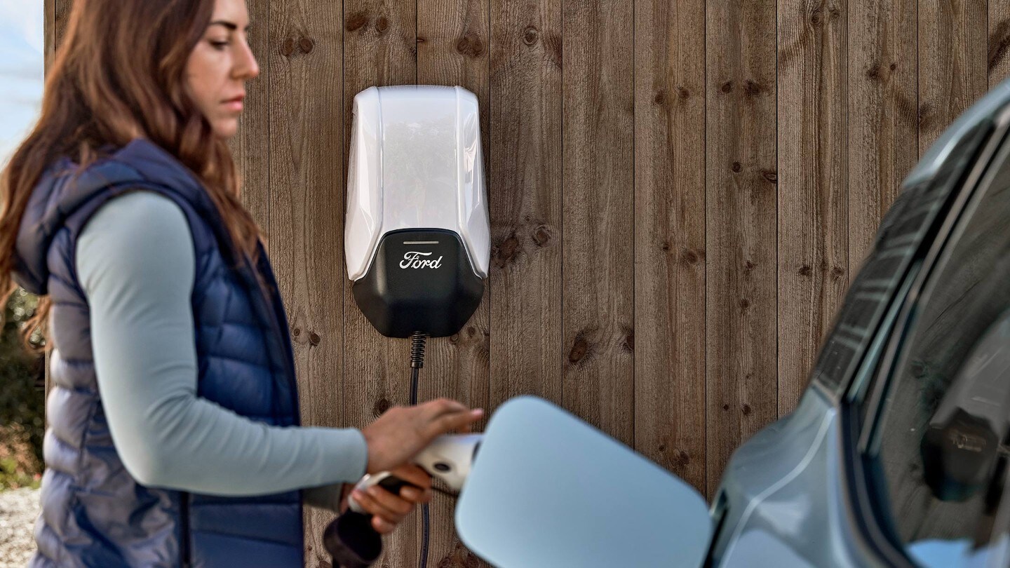 Une femme branche le nouveau Ford Explorer à la Ford Wallbox avec un câble de charge