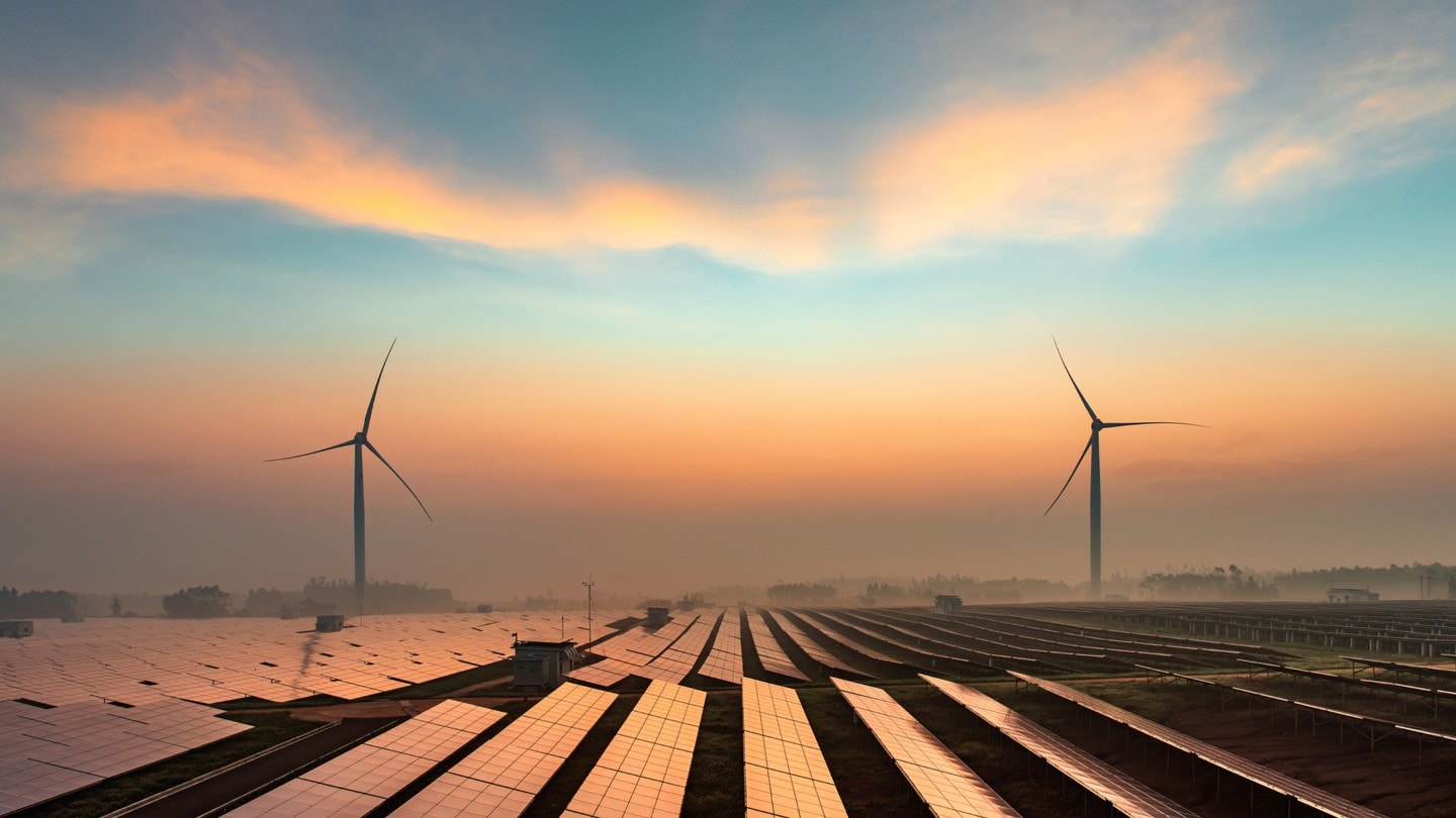 Champ de modules photovoltaïques avec deux éoliennes au loin