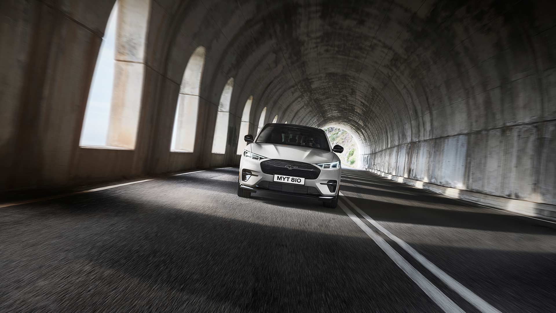 Une Ford Mustang Mach-E électrique de couleur argentée roule dans un tunnel. 