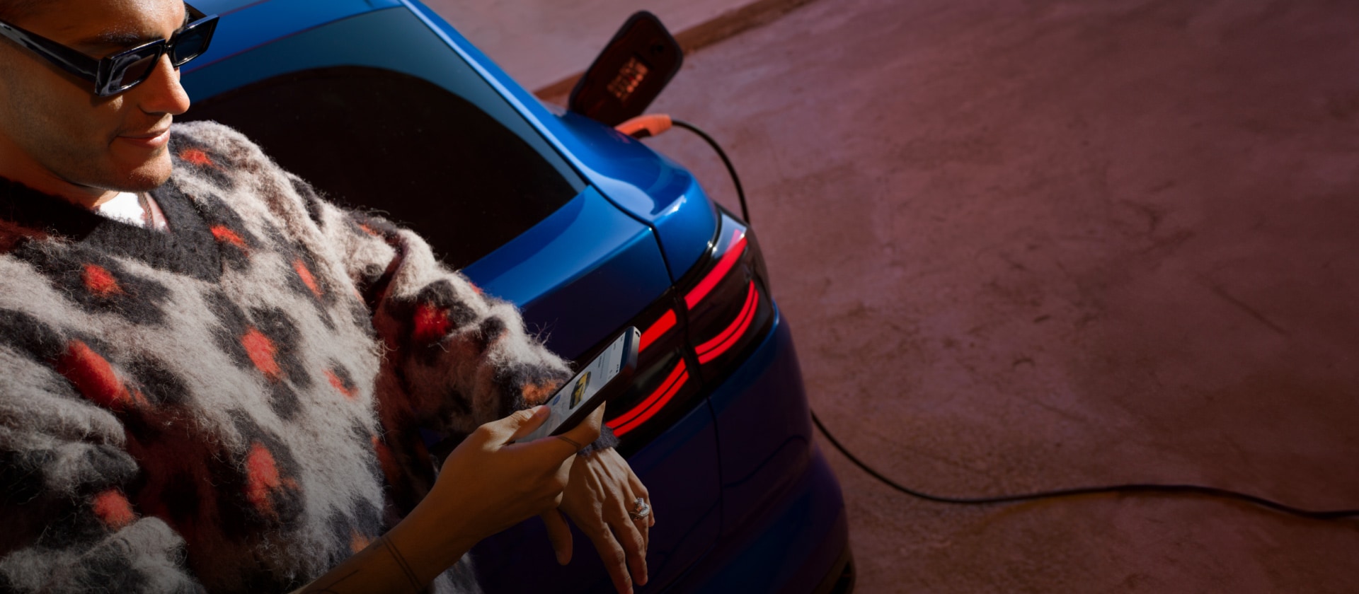 Une personne recharge une Ford Capri électrique bleue sur une borne publique. 