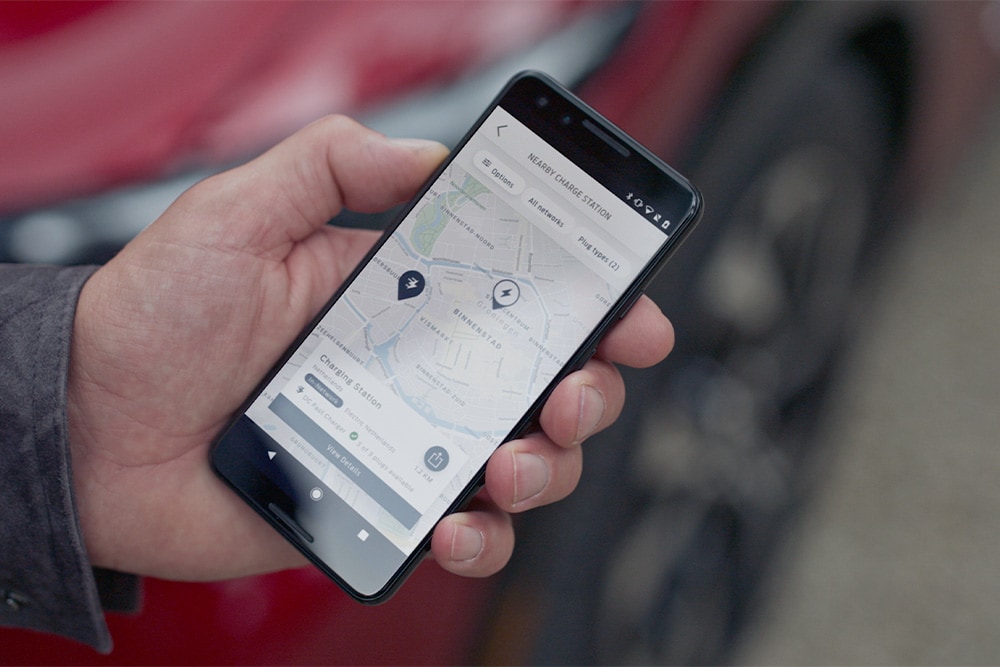 Un smartphone affiche l’application FordPass™ avec les bornes de recharge publiques pour véhicules électriques Ford à proximité.