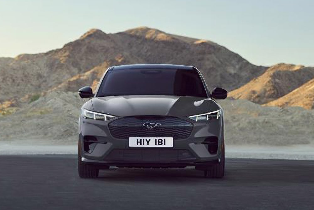 Vue avant d'un Ford Mustang Mach-E noir, garé devant un paysage montagneux.