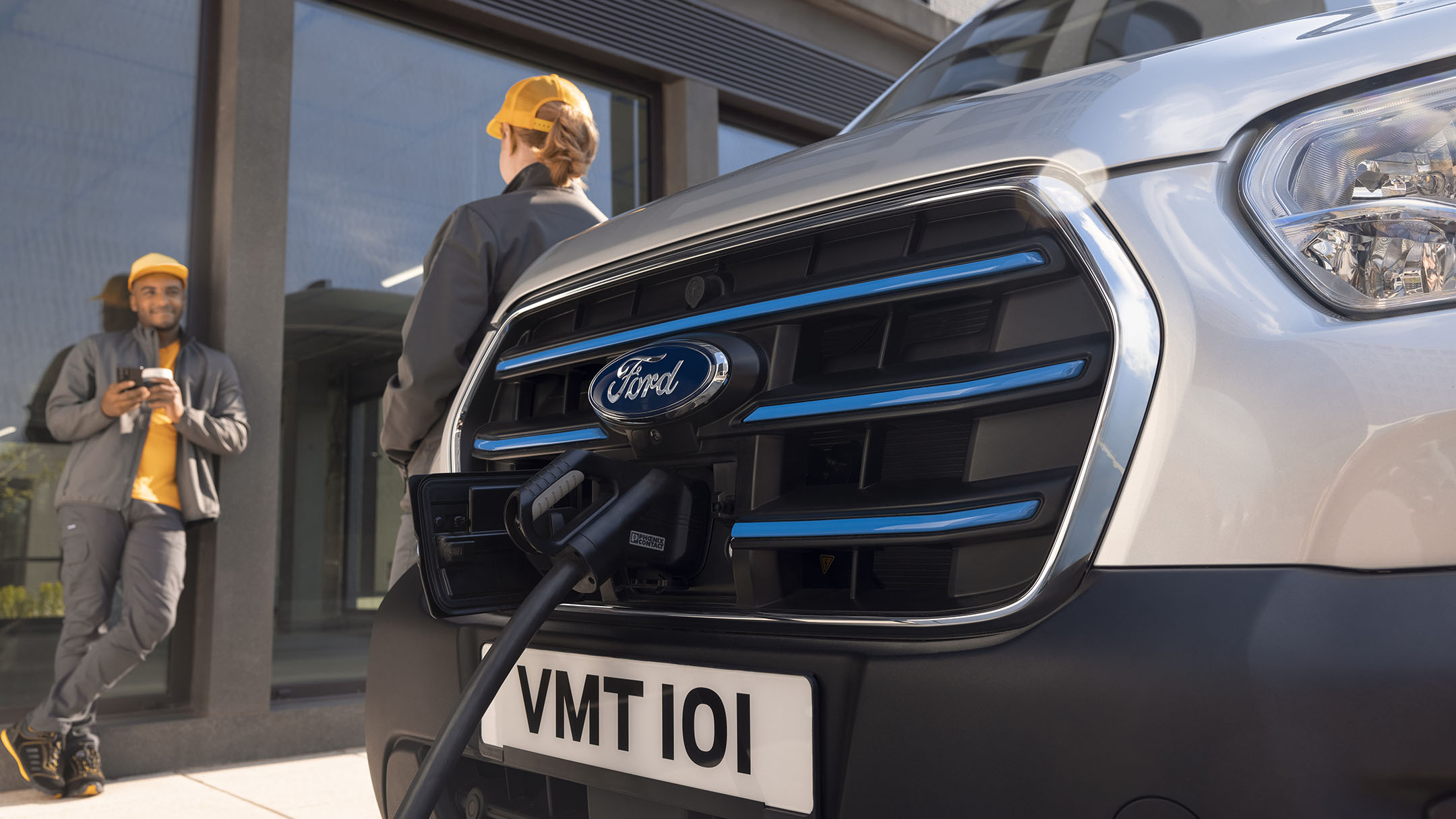 Ford E-Transit en cours de chargement, vue détaillée, plus deux personnes en train de parler