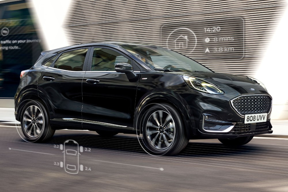 Ford Puma couleur noire Vue de face aux trois quarts, scène de conduite devant un bâtiment moderne