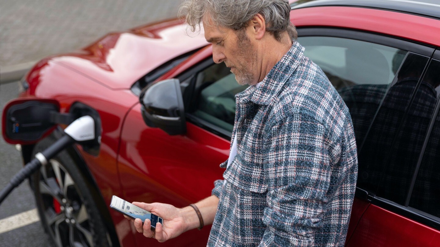 Homme consultant son smartphone, appuyé contre une borne de recharge