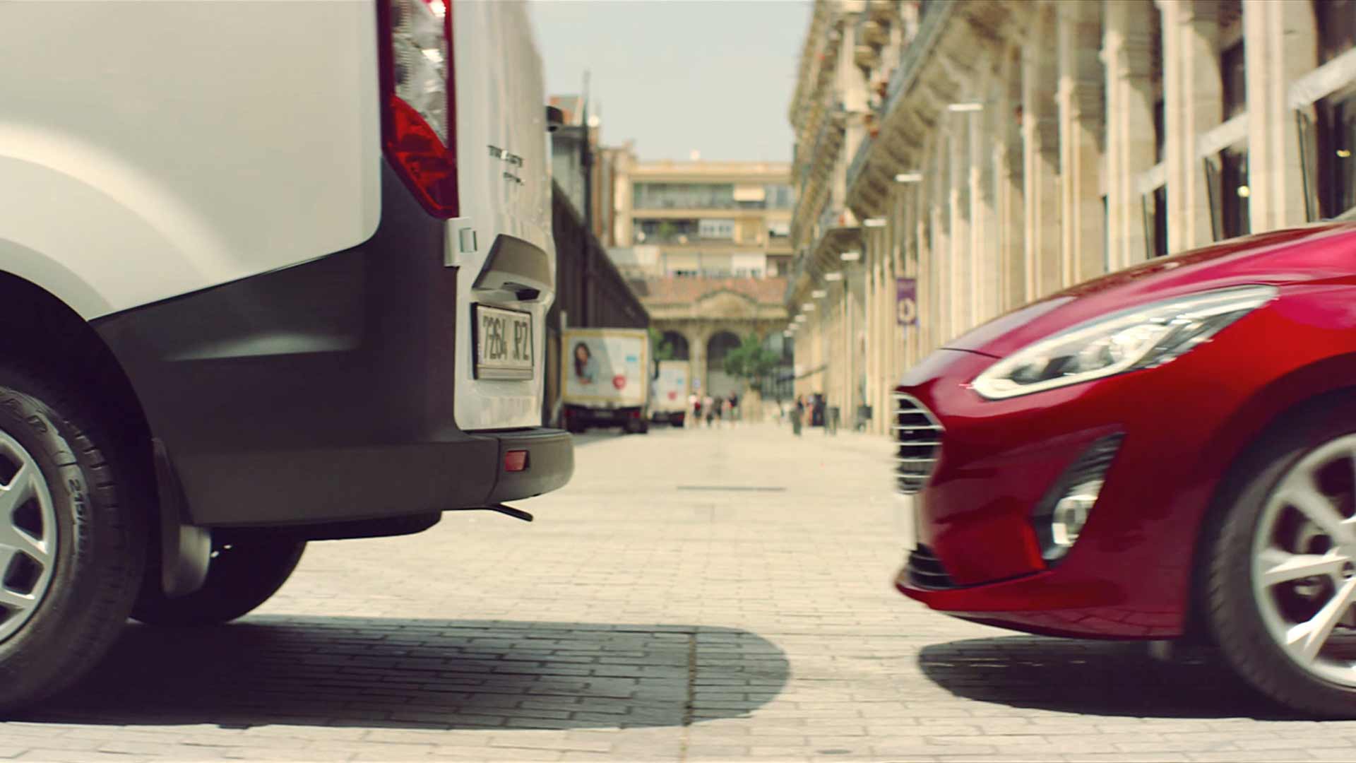 Ford Fiesta ST couleur rouge. Vue partielle latérale de l’avant, véhicule se trouvant derrière un Ford Transit blanc.