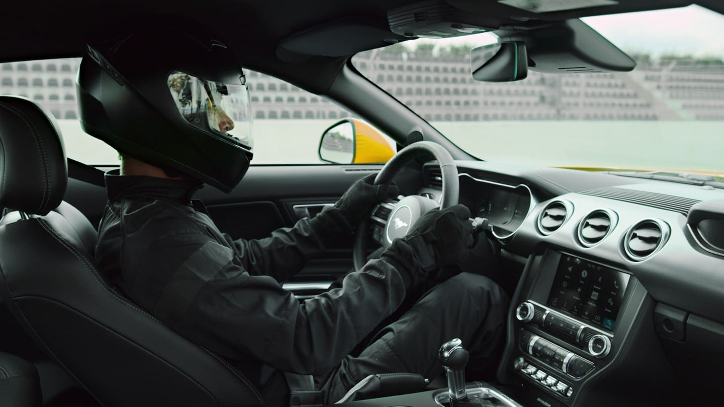 Ford Mustang Vue intérieure du siège passager avec pilote de course au volant, portant un casque noir