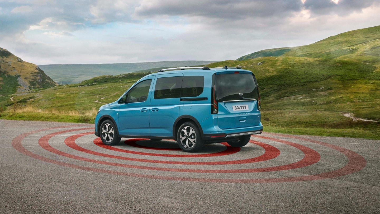 Ford Tourneo Connect couleur bleue, vue arrière aux trois quarts, se garant dans un environnement accidenté avec illustration alarme antivol