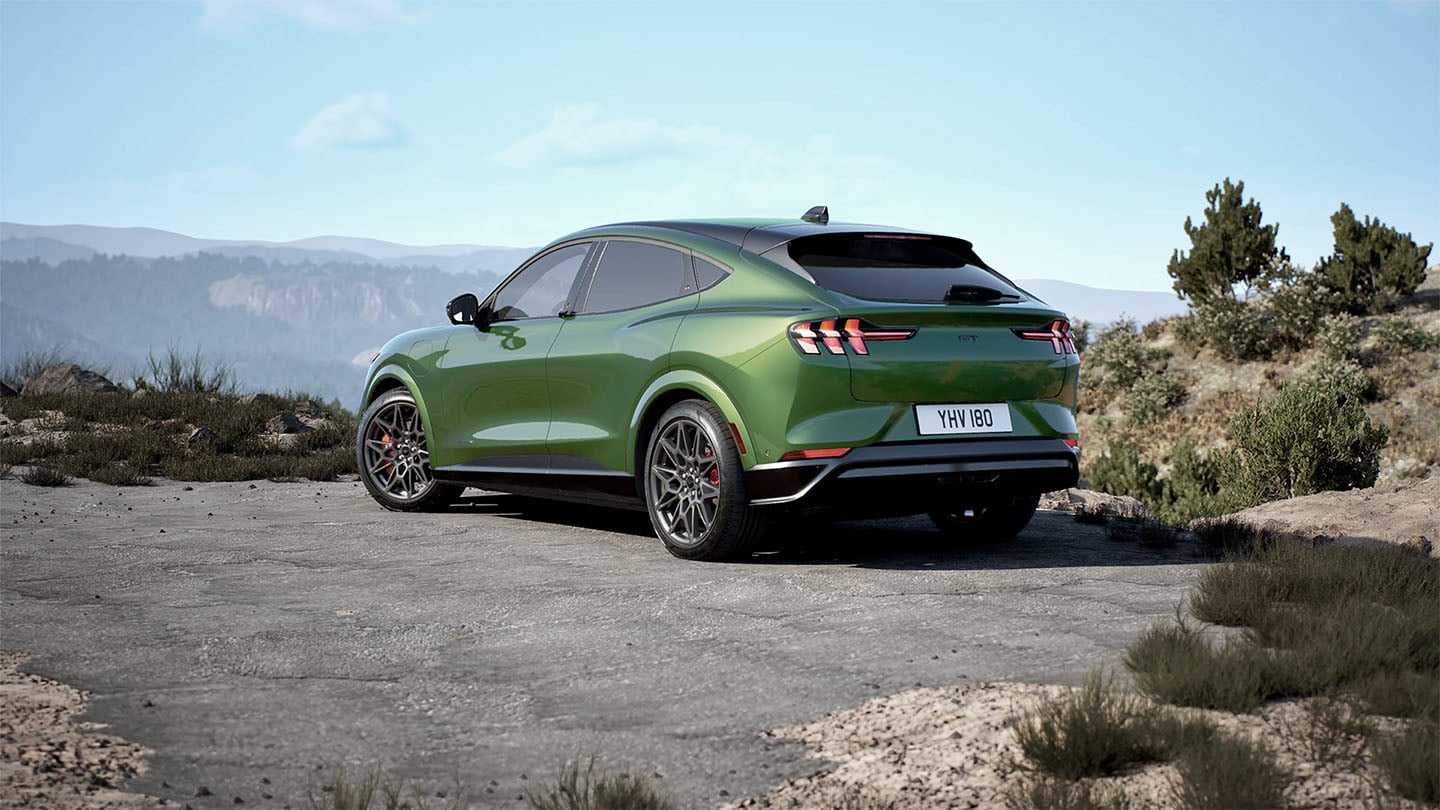 Vue arrière de la Ford Mustang Mach-E GT de couleur verte stationnée le long d’une route de montagne.