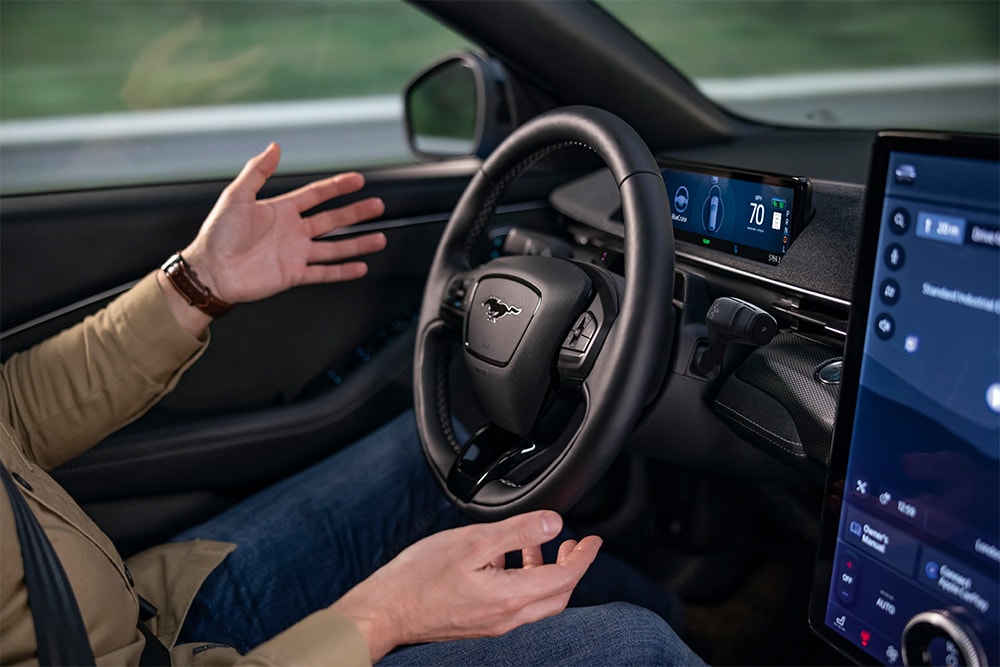 Les mains du conducteur à distance du volant de la Mustang Mach-E, illustrant la technologie BlueCruise pour la conduite autonome.