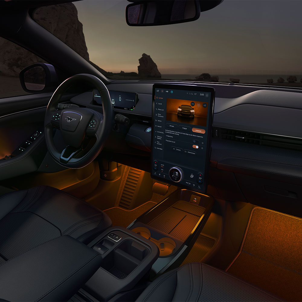 Ford Mustang Mach-E la nuit, avec l’écran tactile SYNC 4 de 15.5 pouces et l’éclairage d’ambiance à LED réglé sur la couleur orange.