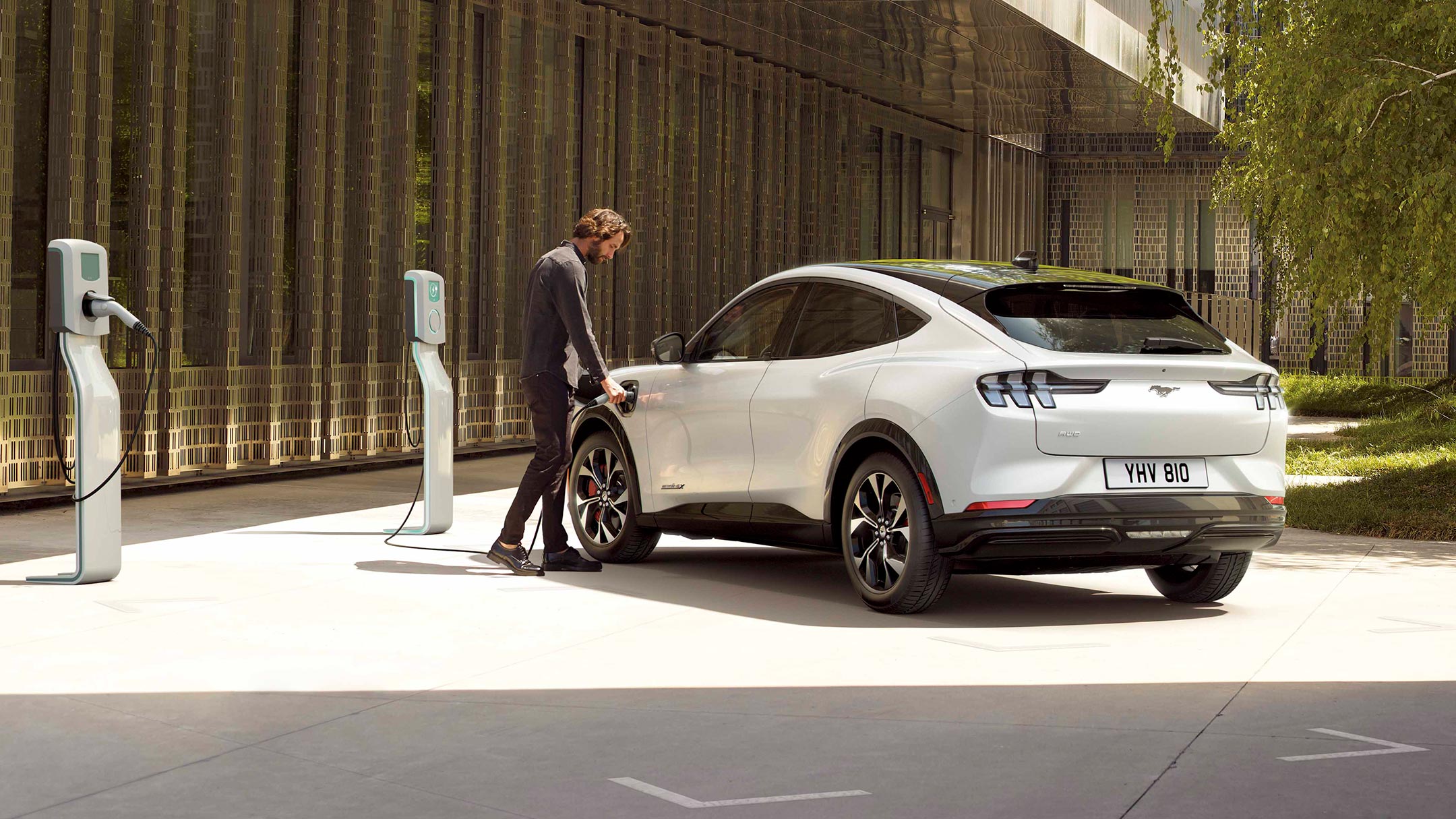 A man charging an all-new Ford Mustang Mach-E