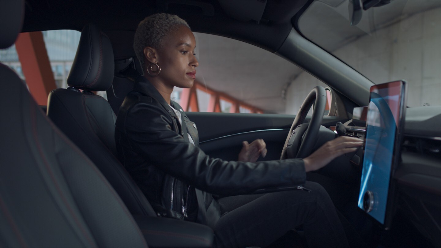 Ford Mustang Mach-E. Vue de l’habitacle. Une femme utilise l’écran tactile Ford SYNC 4