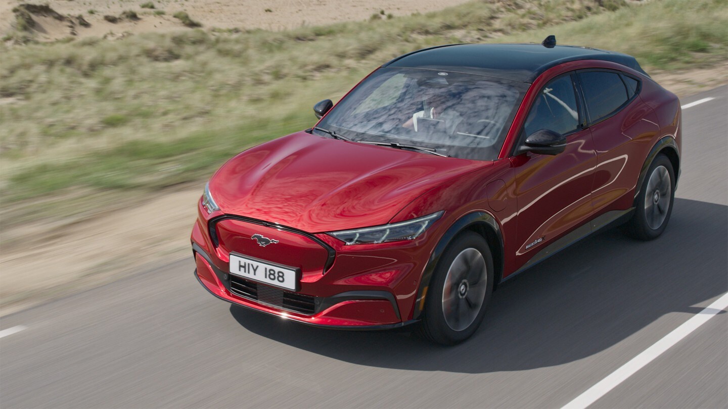 Ford Mustang Mach-E couleur rouge. Vue avant aux trois quarts. Conduite; AWD sur une route de campagne