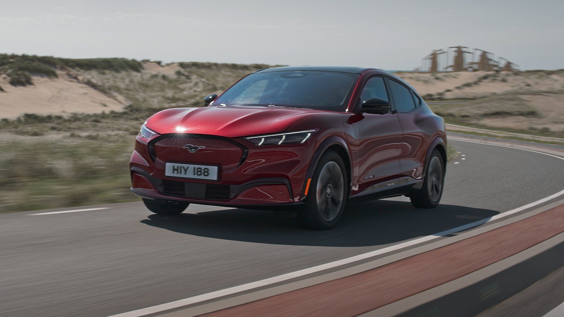 Une Ford Mustang Mach-E rouge roule sur une route de campagne