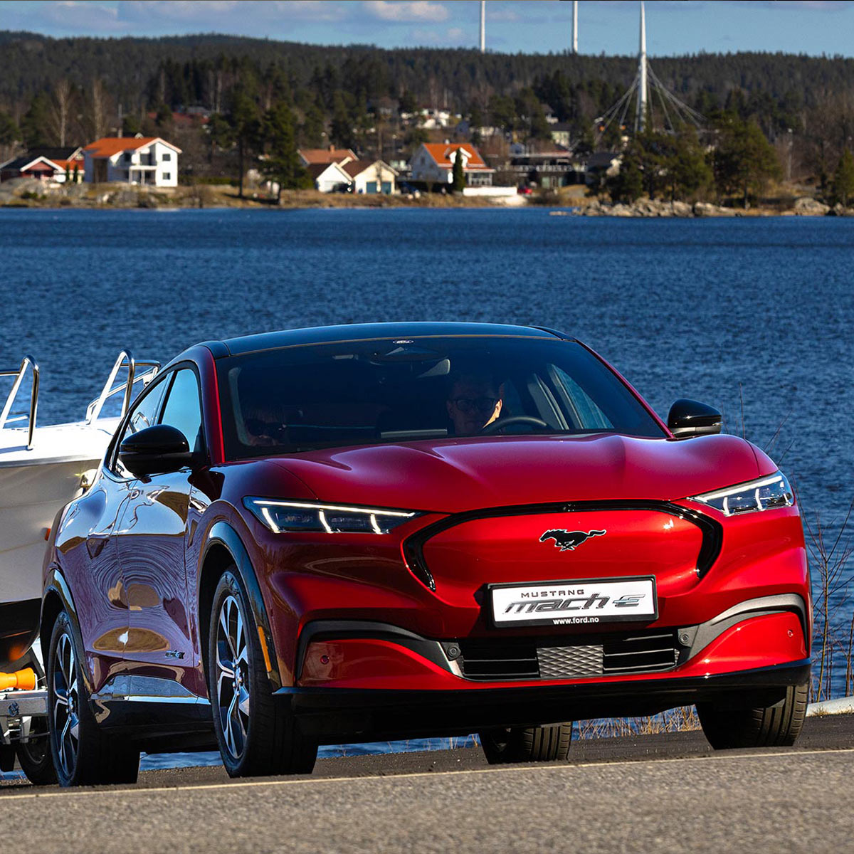 Ford Mustang Mach-E rouge vue de face tractant un bateau sur une remorque dans un lac