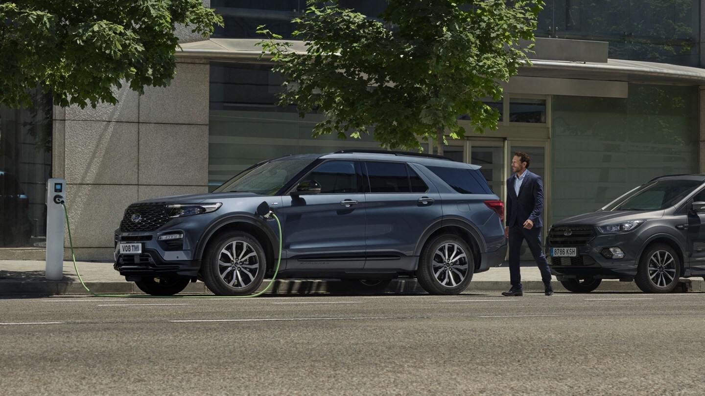 Ford Explorer Plug-in Hybrid en bleu. Vue de côté. Stationné à une station de recharge