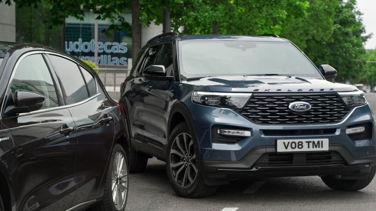 Ford Explorer Plug-In-Hybrid  bleu. Vue de trois-quarts avant. Se garant dans une place de parking étroite 