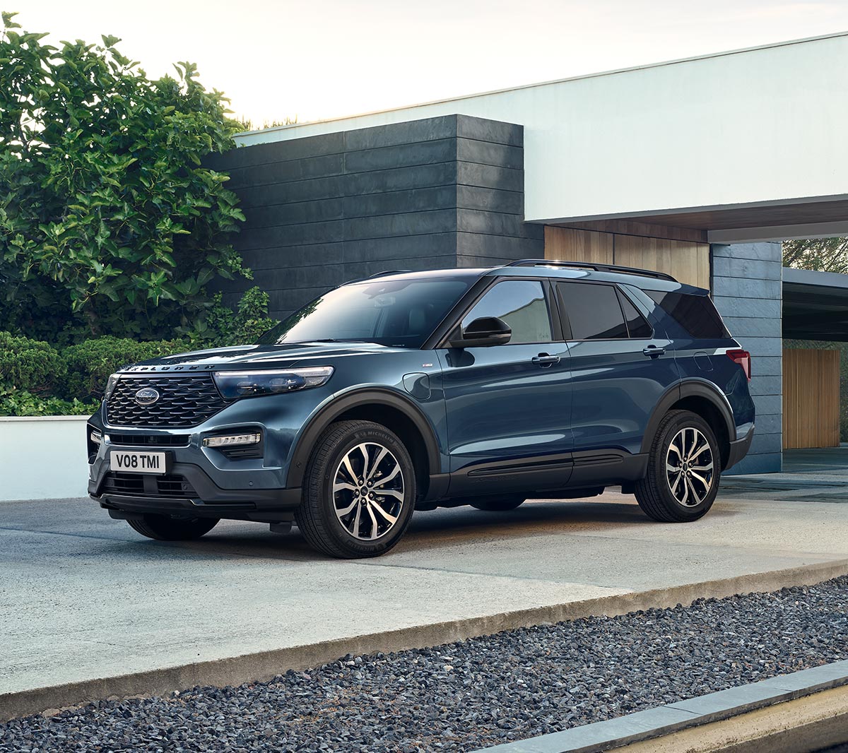 Ford Explorer Plug-In Hybrid bleu. Vue trois-quarts avant. Stationné devant un édifice moderne