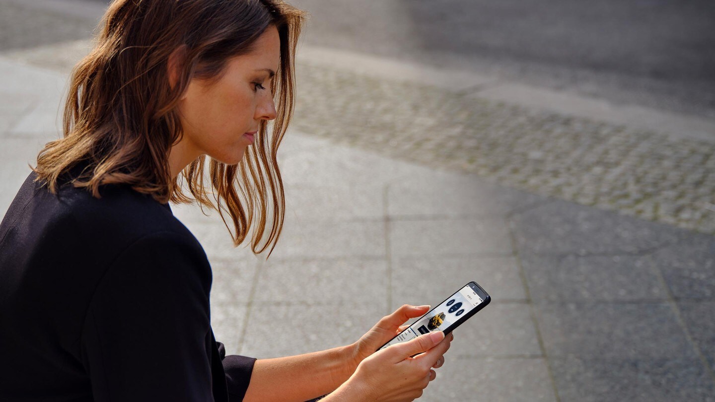 Femme assise sur le bord de la route regardant son smartphone