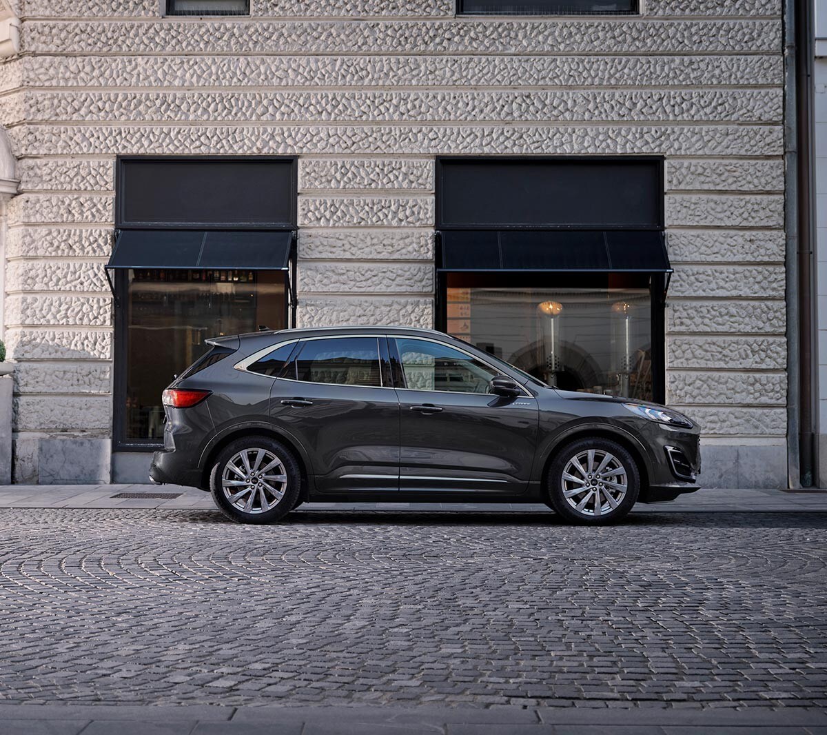 Ford Kuga couleur bleue. Vue latérale, devant un magasin