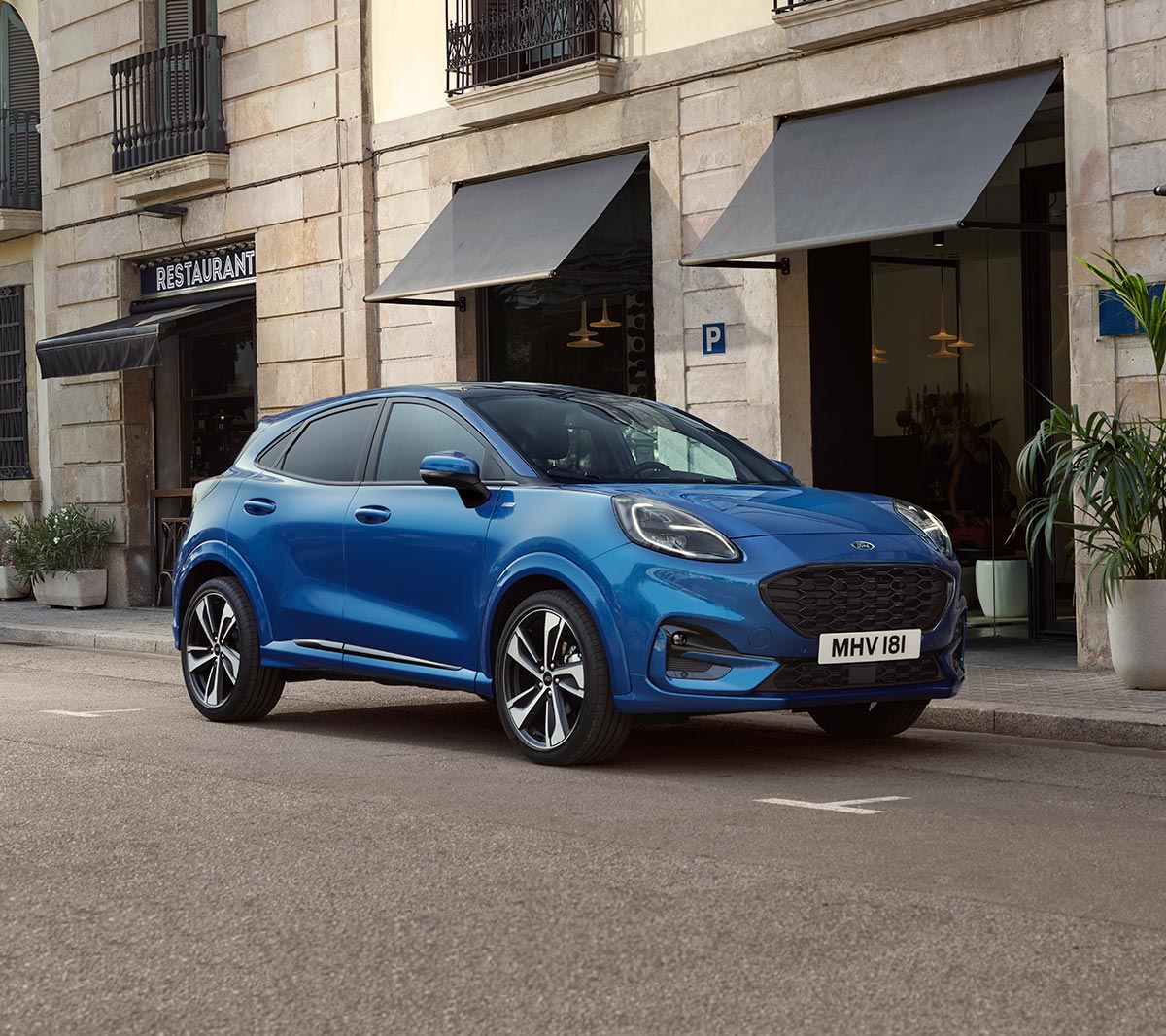 Ford Puma couleur bleue. Vue de trois quarts, se garant devant un restaurant