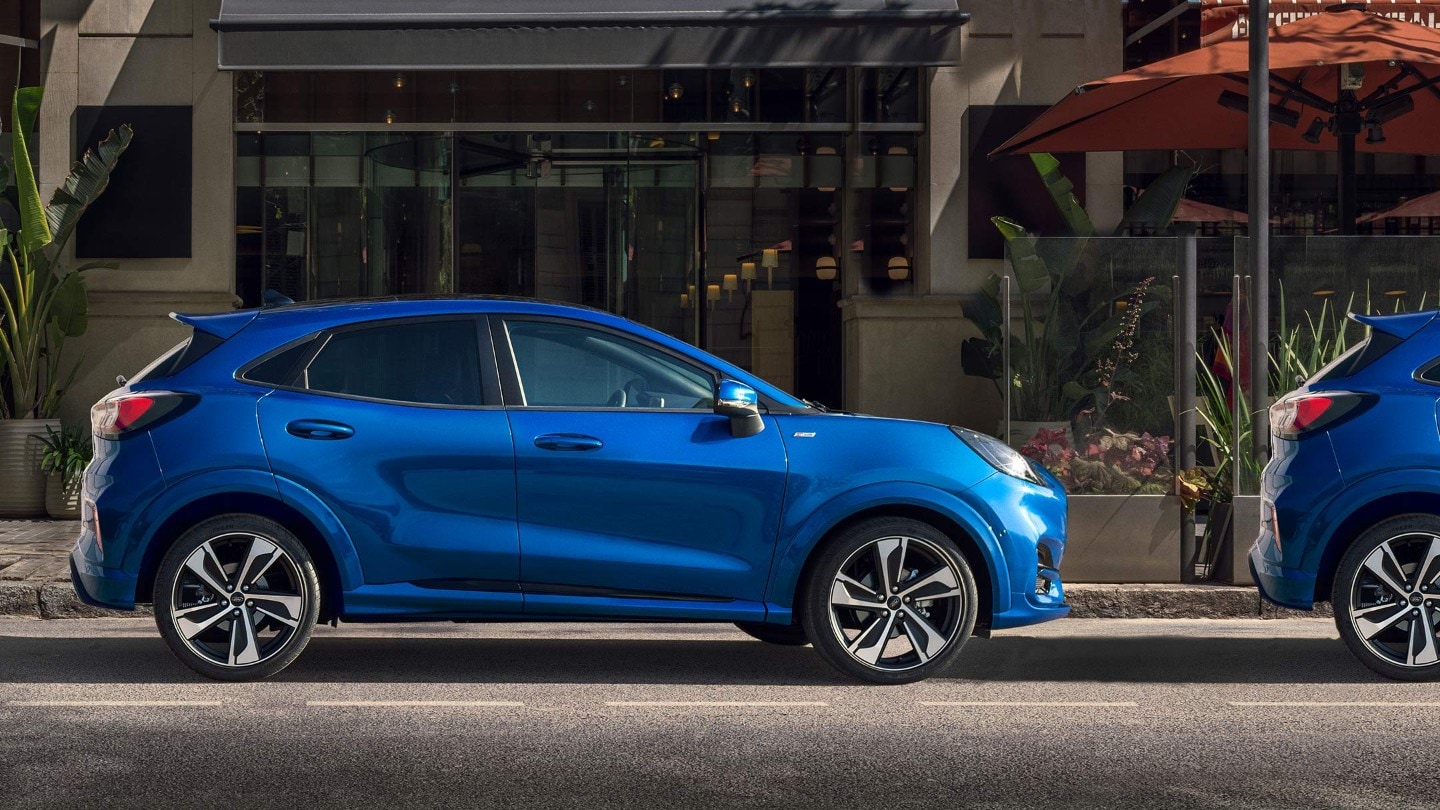 Ford Puma ST-Line X couleur bleue, vue latérale, stationnant sur une place libre devant une maison.