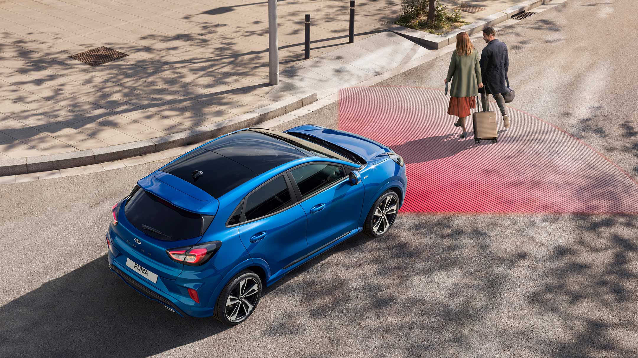 Le Ford Puma ST-Line X couleur bleue, vu de l’arrière, dans une rue. Deux piétons à l’avant.