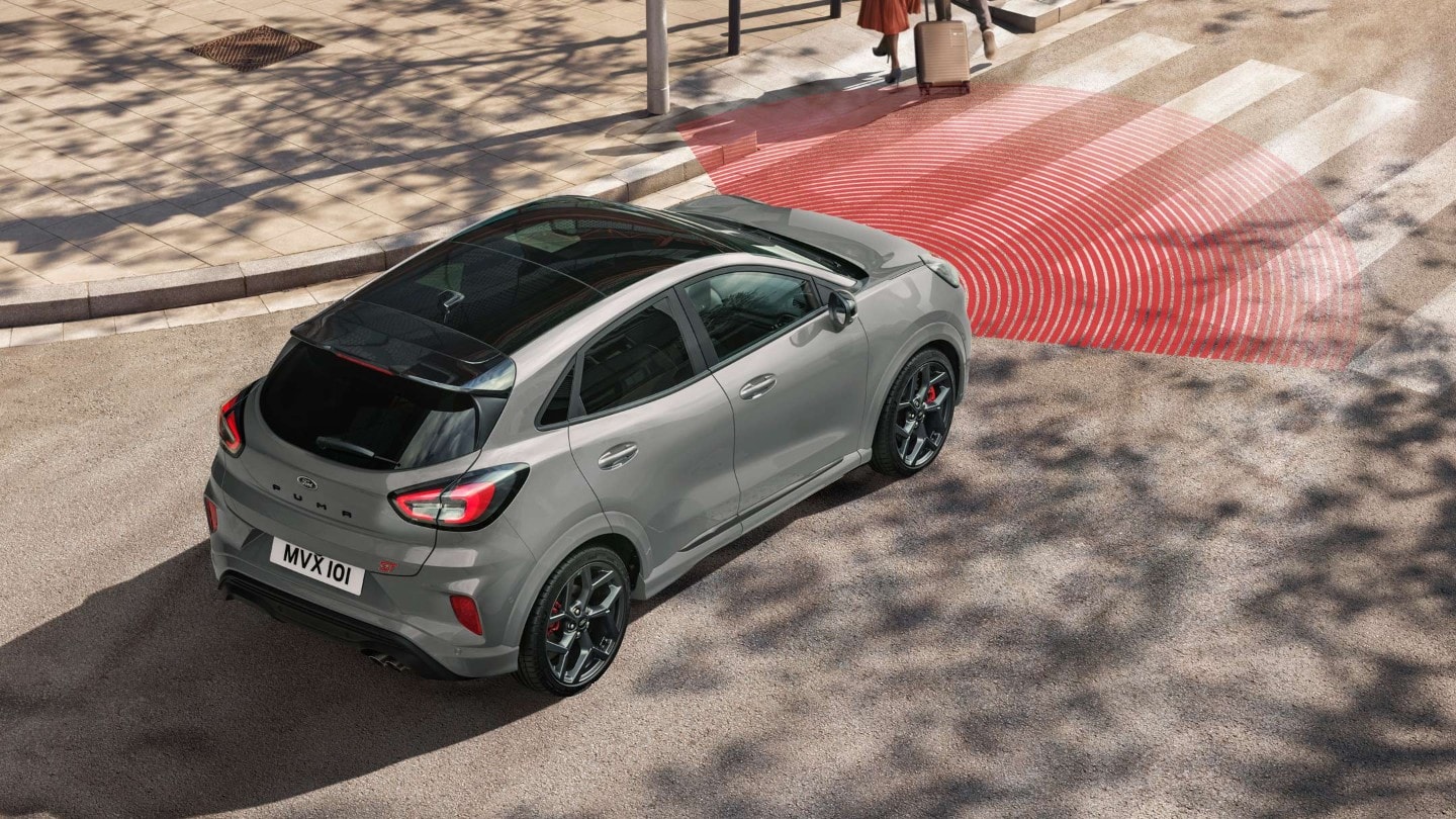 Le Ford Puma ST-Line X couleur bleue, vu de l’arrière, dans une rue. Deux piétons à l’avant.