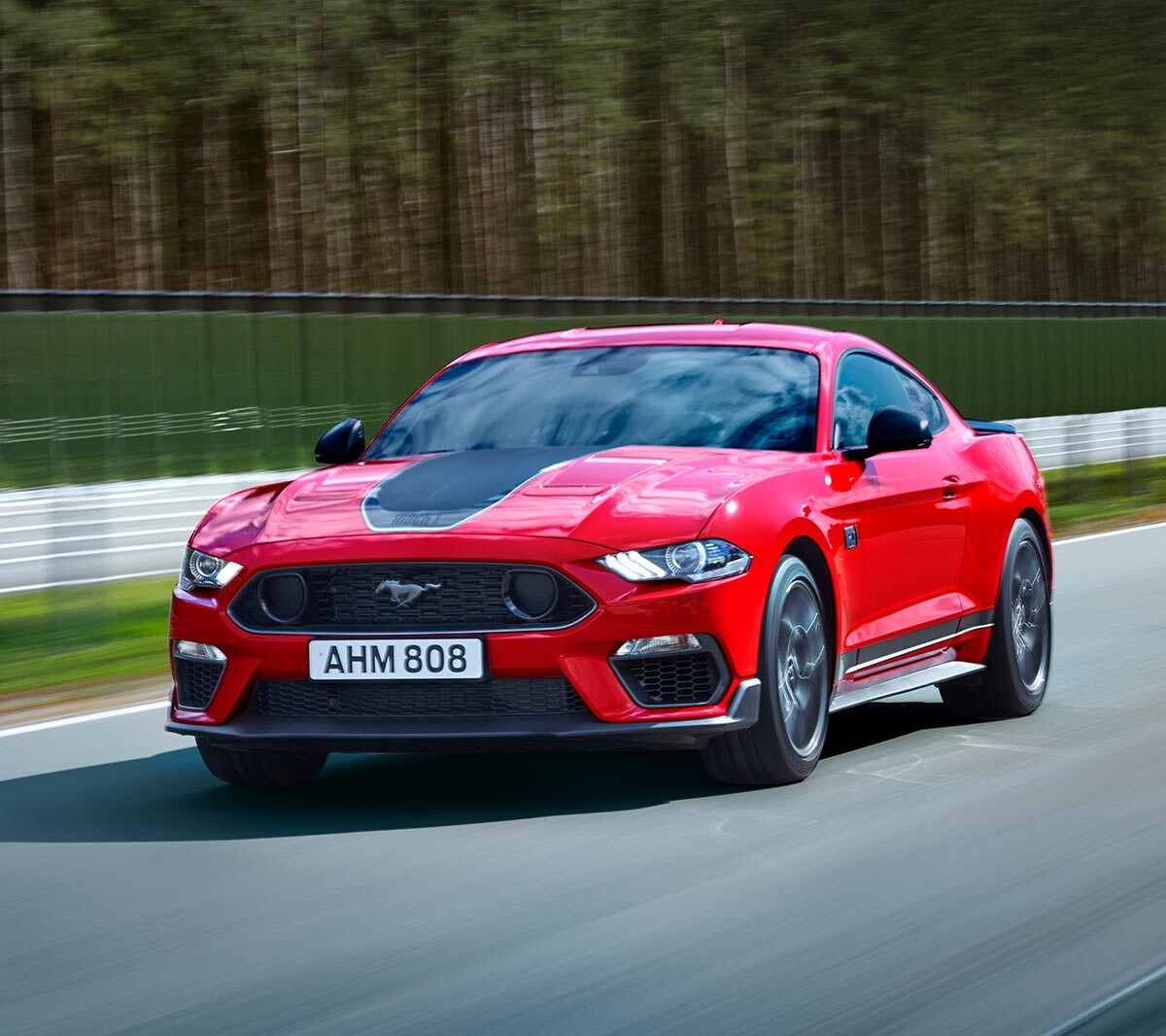 Ford Mustang Mach 1 couleur rouge. Vue de face aux trois quarts, roulant sur un circuit.