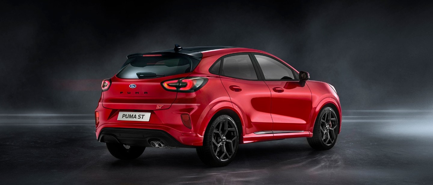 Ford Puma ST couleur rouge. Vue arrière aux trois quarts, à l’arrêt dans un showroom sombre