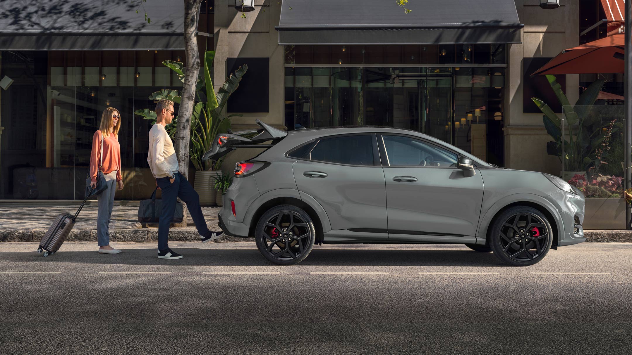 Ford Puma ST couleur grise. Vue latérale rapprochée, un homme ouvre le hayon commandé par capteur d’un mouvement du pied