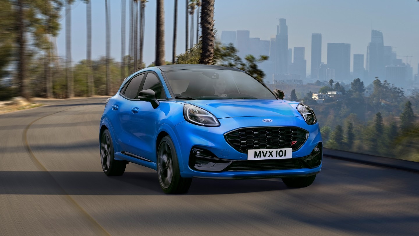 Ford Puma ST Powershift couleur bleue, vue de face aux trois quarts, roulant sur une route sinueuse