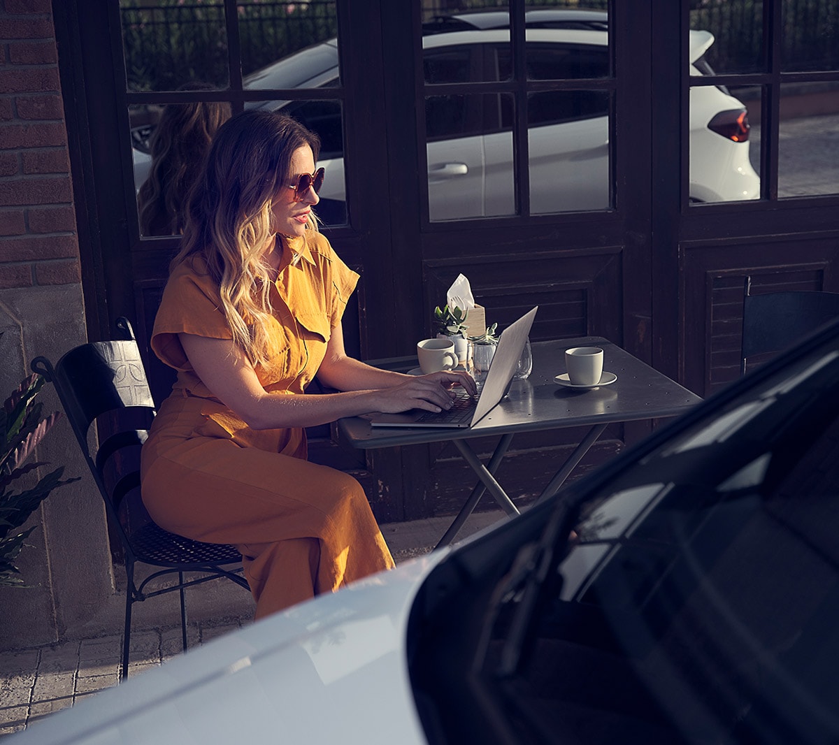 Ford Fiesta couleur blanche. Vue détaillée de l’avant, stationnant devant un café avec une femme à l’arrière-plan.