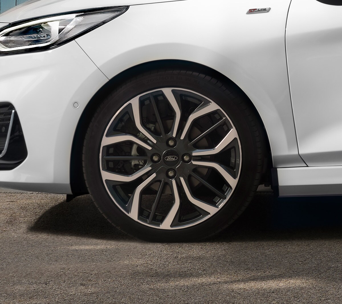 Ford Fiesta couleur blanche. Vue latérale de l’avant, stationnant devant une maison avec une femme au premier plan.