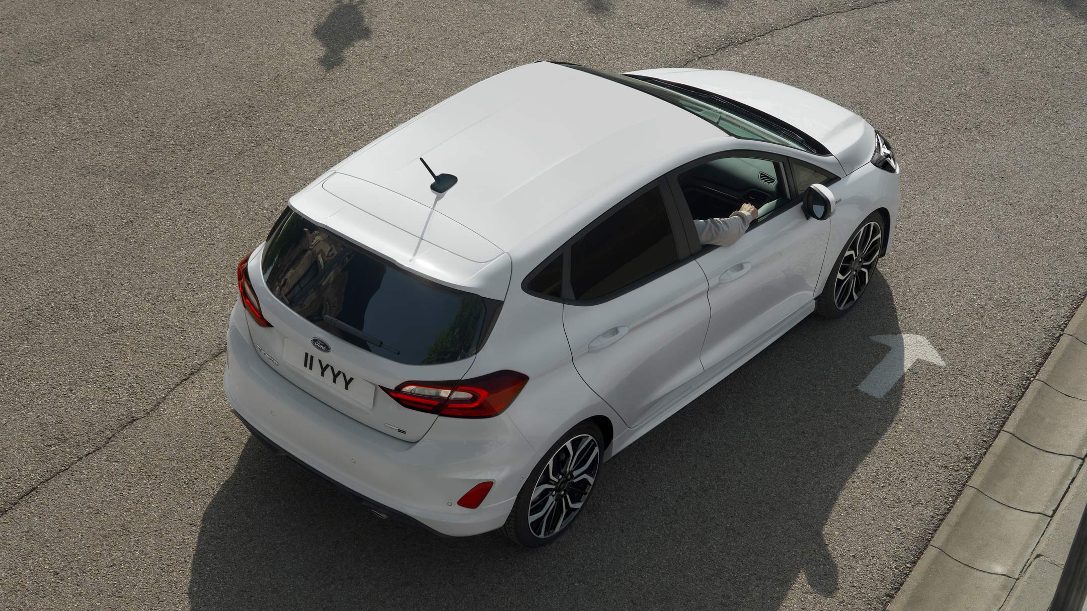Ford Fiesta couleur blanche, vue arrière aux trois quarts d’en haut, roulant sur une route.